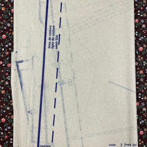 Puede incluir: Una pila de hojas de patr&oacute;n de costura beige con l&iacute;neas azules impresas y texto. El texto incluye "seam line", "couture de 5/8", "vista", "view", "l&iacute;nea del", "ligne de" y "cutting lin".