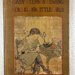 May include: A vintage book cover with a brown background and the title "Easy Steps in Sewing for Big and Little Girls". The cover features an illustration of a girl sitting at a table sewing with a doll beside her.
