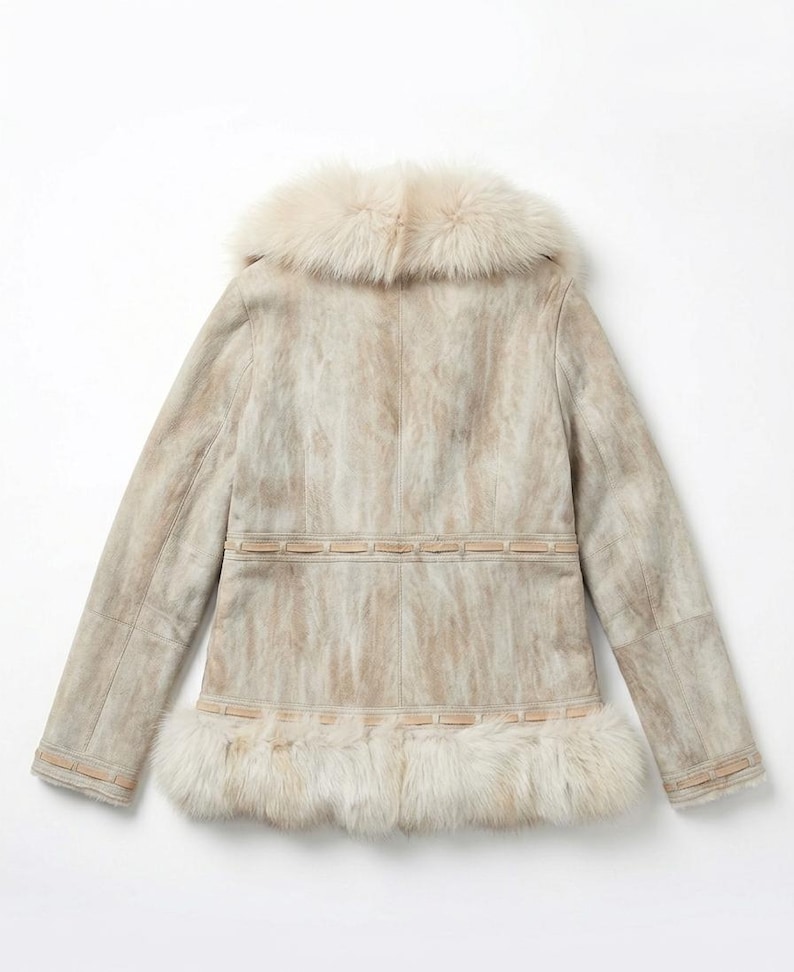 May include: A light-colored suede jacket with a fur collar and trim. The jacket features a textured pattern and a decorative band around the waist and hem. The fur trim is a creamy white color.