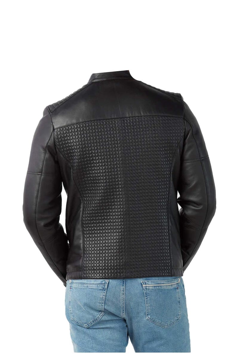 Op de afbeelding: Zwarte leren jas met een gewatteerd rugpaneel en schouderdetails. De jas heeft een klassieke kraag en lange mouwen. De achterkant heeft een gestructureerd, gewatteerd patroon. De jas wordt gedragen met een blauwe jeans.