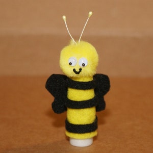 May include: A yellow and black bee finger puppet with a fuzzy head and googly eyes.