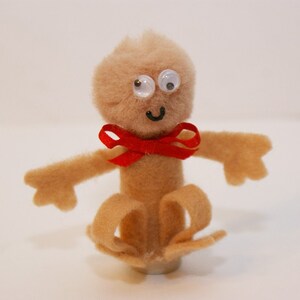 May include: A brown felt finger puppet with googly eyes, a red bow tie, and a smiling face.