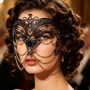 May include: An elaborate black masquerade mask with a filigree design, embellished with rhinestones and gold chains. The mask is designed to cover the eyes. A striking accessory for a ball or themed event.