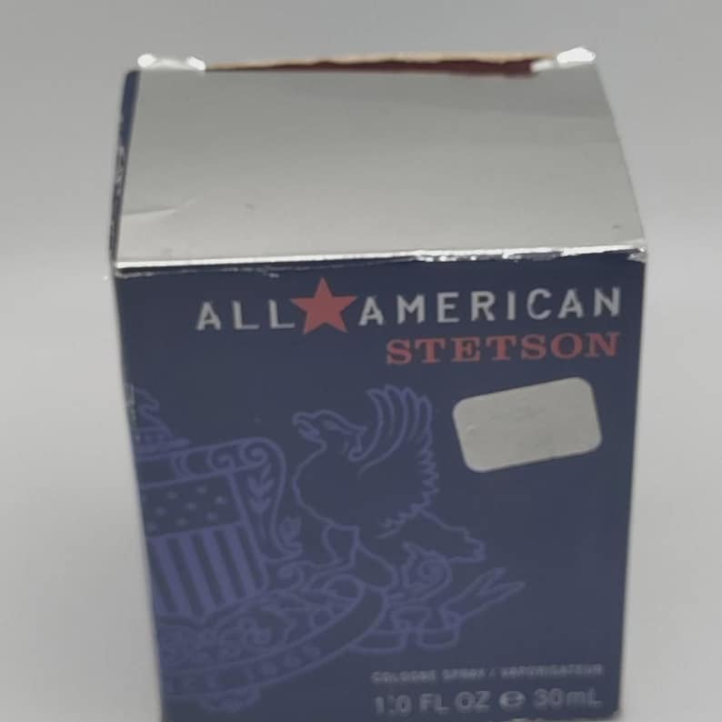 Peut inclure: Bo&icirc;te bleu marine avec un dessus en feuille d'argent. Le texte "ALL AMERICAN STETSON" est affich&eacute; avec une &eacute;toile rouge. La bo&icirc;te pr&eacute;sente un aigle et un bouclier. Le bas de la bo&icirc;te indique "1.0 FL OZ e 30ml".