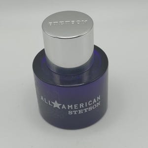 Peut inclure: Flacon de parfum Stetson bleu fonc&eacute; avec un bouchon argent&eacute;. Le flacon porte l'inscription "ALL AMERICAN STETSON" sur le devant. Le bouchon porte l'inscription "STETSON".