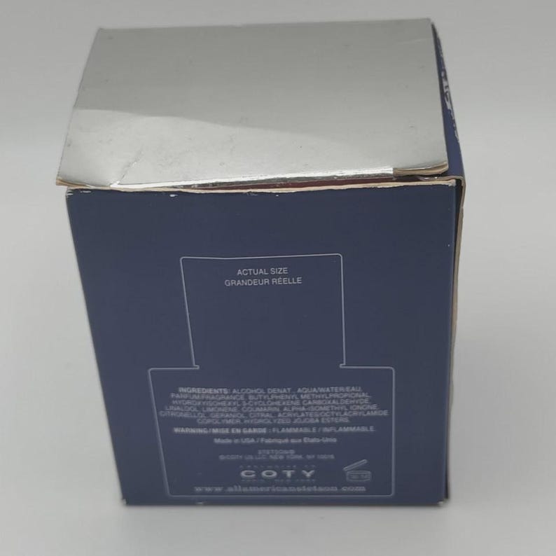 Peut inclure: Une bo&icirc;te de produit bleu marine avec un dessus argent&eacute;. La bo&icirc;te porte le texte "ACTUAL SIZE GRANDEUR REELLE" et des informations sur les ingr&eacute;dients. La marque "COTY" est visible au bas de la bo&icirc;te.