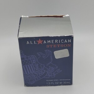 Peut inclure: Une bo&icirc;te bleu marine de parfum Stetson. La bo&icirc;te pr&eacute;sente les mots "ALL AMERICAN STETSON" en blanc et rouge, ainsi qu'une illustration d'un aigle et le texte "COLOGNE SPRAY / VAPORISATEUR 30ml".