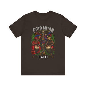 Op de afbeelding: Donkerbruin t-shirt met een grafisch ontwerp. Het ontwerp bevat de tekst "POTO MITAN" en "HAITI". De afbeelding toont twee mensen die drums spelen, met een centrale paal en kleurrijke linten.