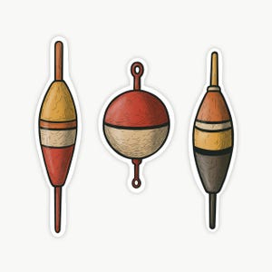 May include: Three fishing bobbers with a hand-drawn aesthetic. The left bobber is elongated with yellow, white, and red sections. The center bobber is round, split between red and beige. The right bobber is elongated with tan, yellow, and dark brown.