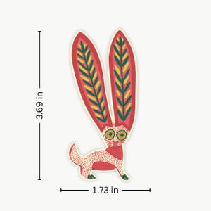 Peut inclure: Un autocollant fantaisiste repr&eacute;sentant un lapin stylis&eacute; avec de grandes oreilles rouges orn&eacute;es de motifs de feuilles vertes et jaunes. Le corps du lapin est rouge et blanc, avec des yeux verts. L'autocollant mesure 9,37 cm de haut et 4,39 cm de large.