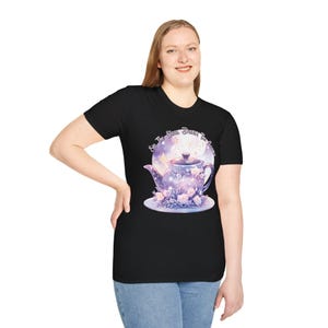 Puede incluir: Camiseta negra con una tetera morada con estrellas y una luna. El texto "Sip the Stars, Drink Tea, Dream" está impreso en la camiseta.