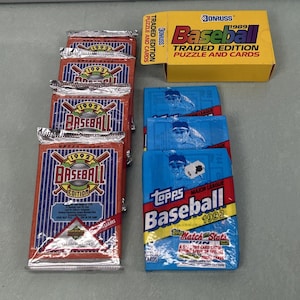 Puede incluir: Una colección de cromos de béisbol antiguos y un juego de cajas. Los paquetes son rojos, blancos y azules con el texto "1992 Baseball Edition". La caja es amarilla con el texto "Donruss Baseball".