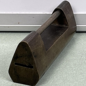 Pode incluir: Um cadeado vintage de latão em forma triangular com uma pega de madeira. O cadeado está fechado e tem uma fechadura na frente.