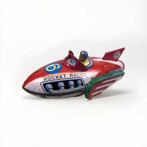 May include: A vintage toy rocket racer in red, white, and green. The toy has a driver figure and the text "ROCKET RACER" on the side. The number 6 is on the tail fin. A classic collectible toy.