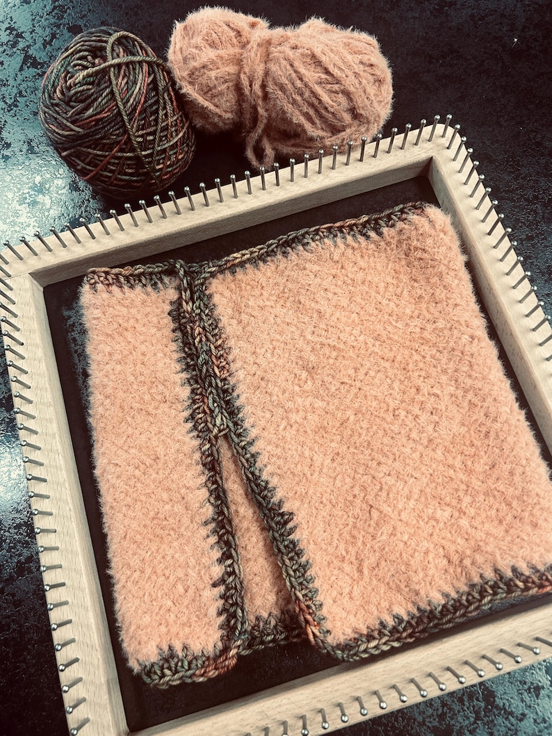 May include: A peach-coloured woven textile is displayed on a wooden loom, with a dark border. Two balls of yarn, one brown and green, and the other peach, are placed near the loom. The textile is likely part of a craft project.