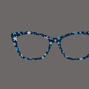 May include: A pair of cat-eye eyeglasses with a dark blue frame. The frame is decorated with a pattern of white and light blue snowflakes. The glasses are set against a gray background.