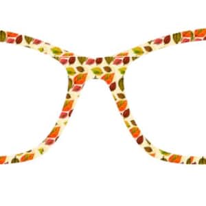 Puede incluir: Gafas de estilo ojo de gato con montura color crema decorada con un estampado de hojas de otoño coloridas en tonos naranja, verde y marrón. Las gafas tienen una forma clásica y femenina.