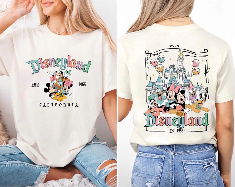 May include: Cream-colored t-shirt featuring the Disneyland logo in pastel colors with Mickey Mouse and friends. The back of the shirt displays a castle and more characters. The text "EST 1955" and "CALIFORNIA" are also visible.