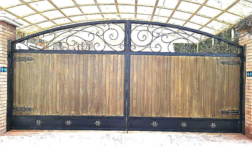 Handmade wrought iron farmhouse gate with arched scrollwork crown and wood-tone panel finish