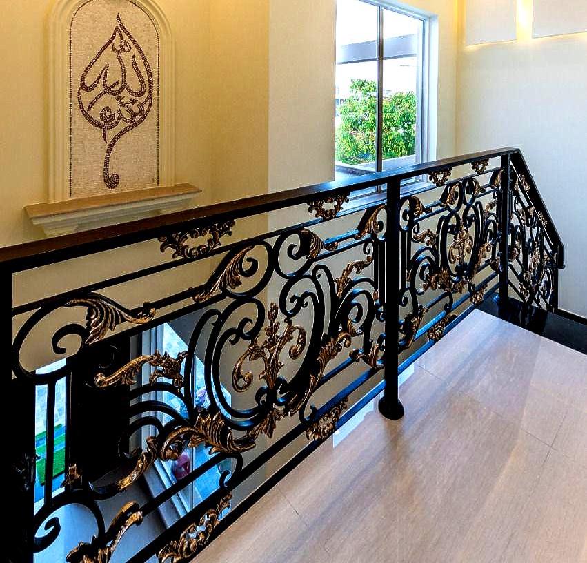 Handmade wrought iron staircase railing with gold accent scrollwork and cast iron floral inserts