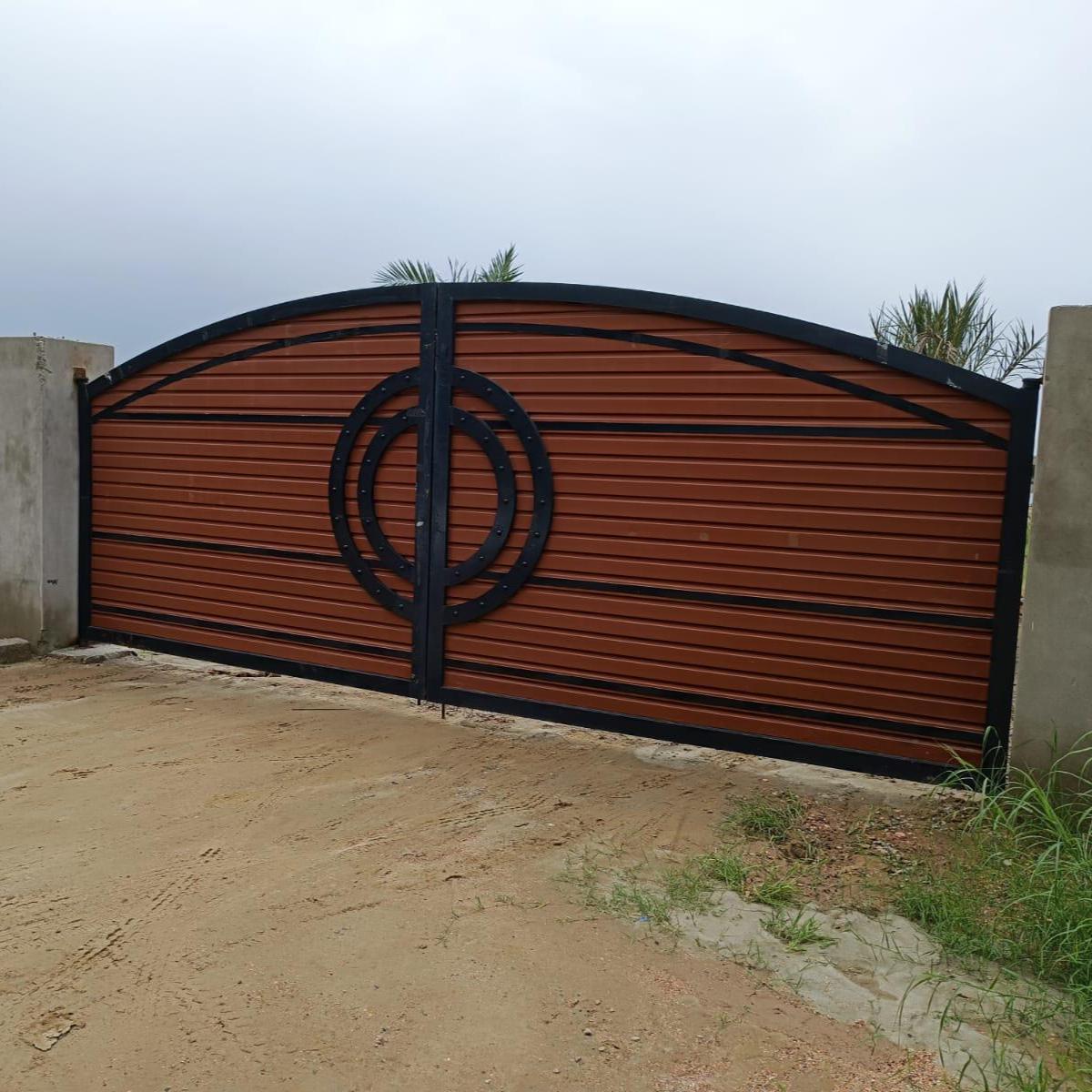 Handmade arched driveway gate with wood-tone cladding and concentric circle motif