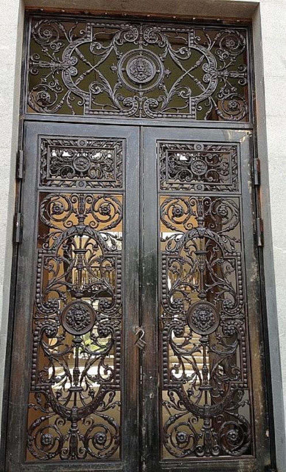 Handmade wrought iron double door with lion crest medallion and scrollwork canopy in aged bronze finish
