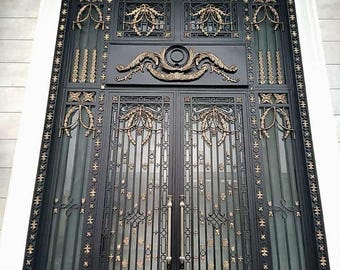 May include: A black metal double door with ornate gold accents and a decorative arched window above. The door has a traditional design with vertical bars and intricate floral patterns.