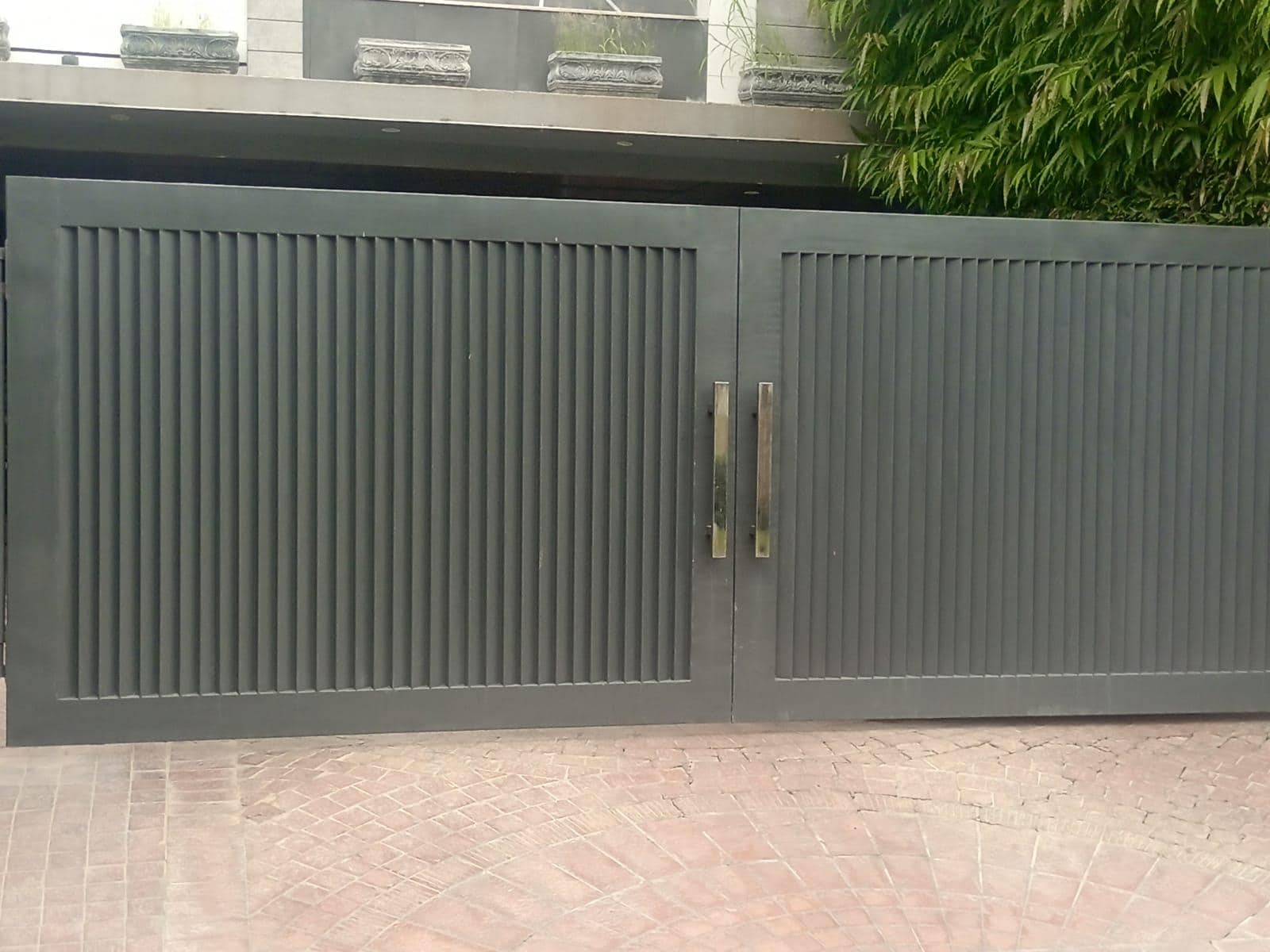 Handmade minimalist iron driveway gate with clean vertical lines and matte grey finish