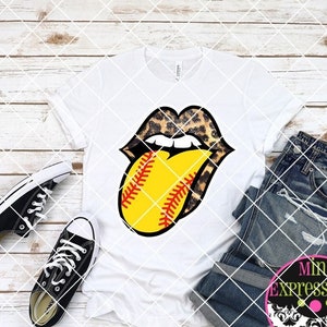 May include: White t-shirt with a graphic of a leopard print tongue sticking out with a softball in the middle. The softball is yellow with red stitching.