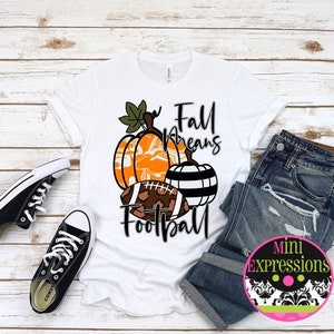 May include: White t-shirt with a graphic of pumpkins and a football with the text "Fall means Football".