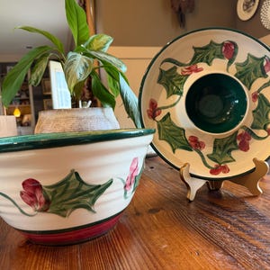 May include: A white ceramic serving bowl and a matching chip and dip platter. The bowl and platter feature a green rim, red berries, and green holly leaf designs. The platter has a central dip bowl.