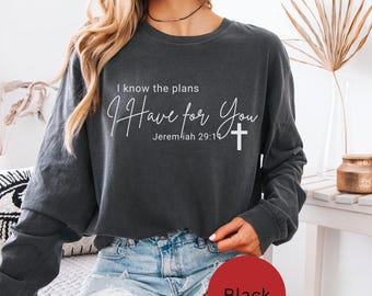 Op de afbeelding: Een antracietgrijs sweatshirt met lange mouwen en ronde hals, voorzien van witte tekst I know the plans I Have for You Jeremiah 29:11 en een klein wit kruissymbool. Het sweatshirt heeft een relaxte pasvorm en een effen donkere kleur.