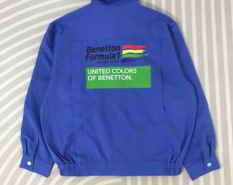 May include: A blue jacket with the Benetton Formula 1 Racing Team logo on the back. The logo includes the text "Benetton Formula 1 Racing Team" and "UNITED COLORS OF BENETTON" in white text on a green rectangle. The jacket has a button closure.