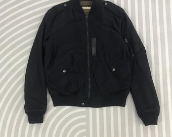 Puede incluir: Chaqueta bomber negra con cremallera, dos bolsillos delanteros y un pequeño bolsillo en la manga izquierda. La chaqueta tiene cuello, puños y dobladillo de canalé. La chaqueta tiene un detalle de cuero en el pecho.