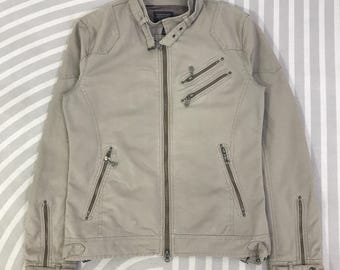 May include: A beige jacket with a stand-up collar and multiple zippered pockets. The jacket has a full-length zipper closure and zippers on the sleeves. The jacket is made of a smooth, possibly synthetic material.