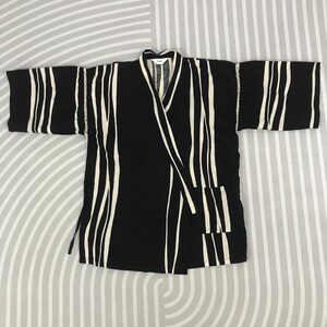 May include: Black and white striped kimono with a wrap closure. The kimono has a relaxed fit and long sleeves.