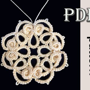 Może przedstawiać: Delikatny, kremowy wisiorek w kształcie płatka śniegu wykonany na szydełku, z bogatym wzorem pętli i węzłów, zwisający na białej nici na czarnym tle. W tle widoczny jest tekst "PDF pattern".