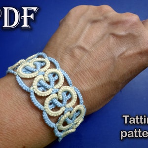 May include: A light blue and cream colored crocheted bracelet with a delicate pattern. The bracelet is worn on a person's wrist. The image includes the text "Tatting pattern".