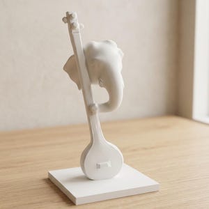 May include: A matte white sculpture featuring the head of an elephant integrated with a stringed musical instrument. The elephant head is positioned at the top of the long neck of the instrument, which rests on a square white base.