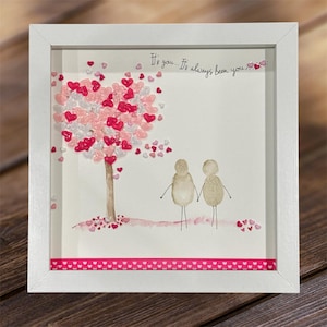 May include: A white framed picture featuring a pink and white heart-shaped tree made of small hearts. The text "It's you... It's always been you..." is written on the white background. Two small figures are holding hands below the tree.