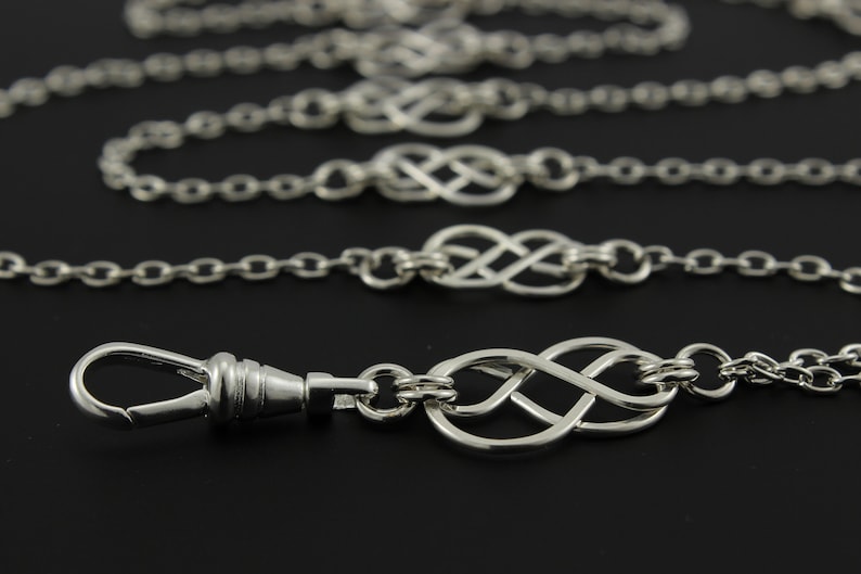 May include: A silver pocket watch chain with a lobster clasp and multiple infinity knot charms.