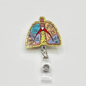May include: Gold glitter badge reel with a colourful anatomical illustration of a lung with the words "upper lobe", "middle lobe", "lower lobe" on each section.
