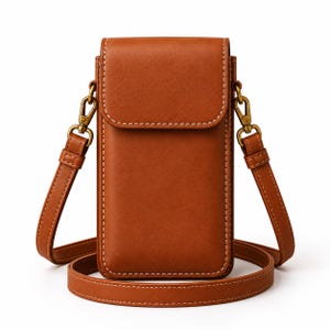 Puede incluir: Un bolso bandolera vertical rectangular de color marrón con cierre de solapa. El bolso presenta costuras blancas en contraste visibles a lo largo de los bordes y una correa ajustable a juego sujeta con herrajes de metal en tono latón antiguo.