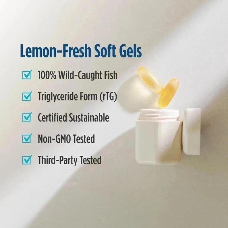 May include: A white bottle with a lid next to it, containing two yellow soft gels. The text reads "Lemon-Fresh Soft Gels" and lists features including "100% Wild-Caught Fish" and "Non-GMO Tested".