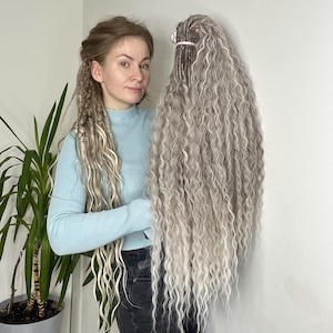 May include: A bundle of long, wavy, gray and white synthetic dreadlocks. The dreadlocks are held together at the top with a white band. The hair is a mix of gray and white, with a natural-looking texture. The dreadlocks are long and flowing.