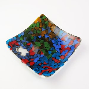 May include: A small, square dish with a mosaic design. The mosaic is made of small, colorful tiles in shades of blue, green, red, and brown.