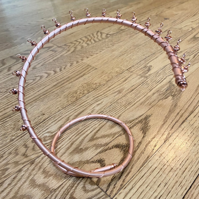 May include: A rose gold metal jewelry stand with a spiral design and multiple hooks. The stand is made of wire and has a smooth, polished finish.