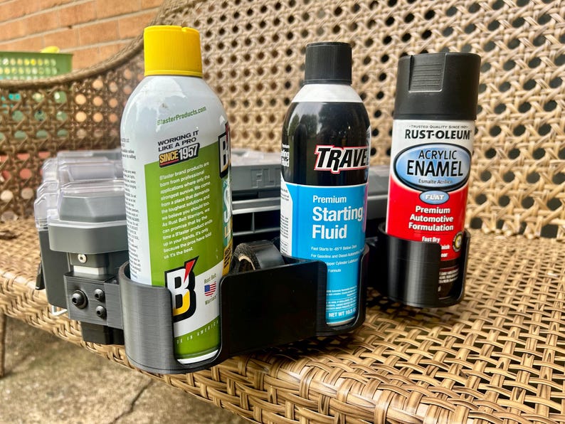 Peut inclure: Un support de rangement en plastique noir dot&eacute; de trois compartiments circulaires, contenant chacun une bombe a&eacute;rosol diff&eacute;rente. Les bombes incluent un produit de marque Blaster &agrave; capuchon jaune, un fluide de d&eacute;marrage Traveler et une peinture Rust-Oleum.