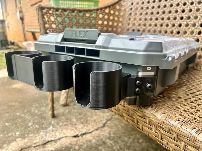 Peut inclure: Une mallette de rangement en plastique gris et noir avec le mot FLEX en relief sur la poign&eacute;e. Deux porte-gobelets cylindriques noirs avec des fentes lat&eacute;rales ouvertes sont fix&eacute;s &agrave; l'avant par un support noir avec des vis visibles.
