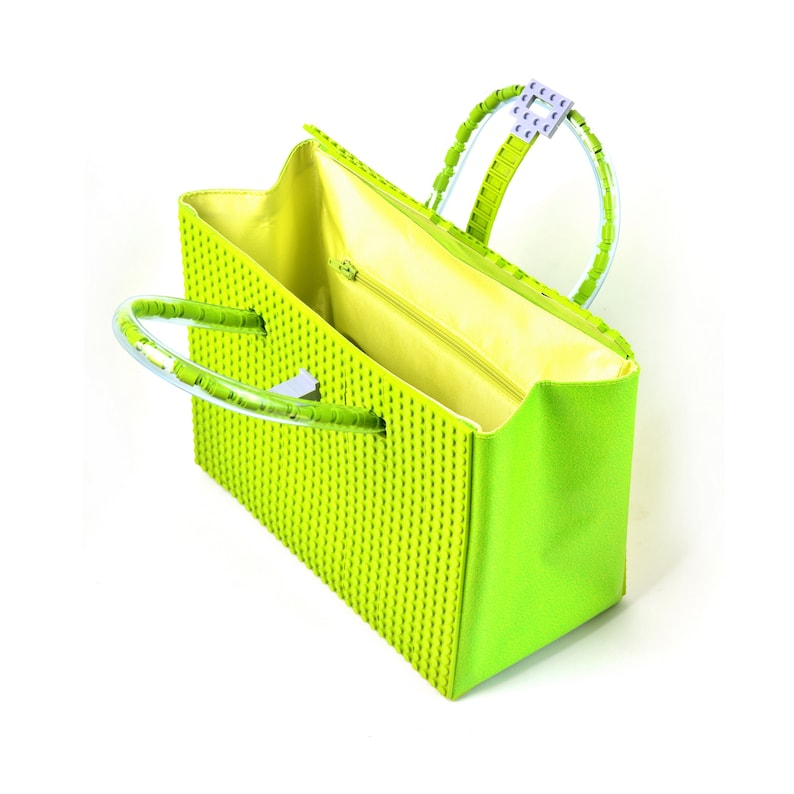 Peut inclure: Un sac &agrave; main vert lime avec des anses en plastique transparent et une fermeture &eacute;clair. Le sac est fait d'un mat&eacute;riau textur&eacute; qui ressemble &agrave; des briques Lego.